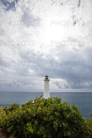 White lighthouse on a steep coast. Dramatic clouds with a view of the sea, pure Caribbean at Le