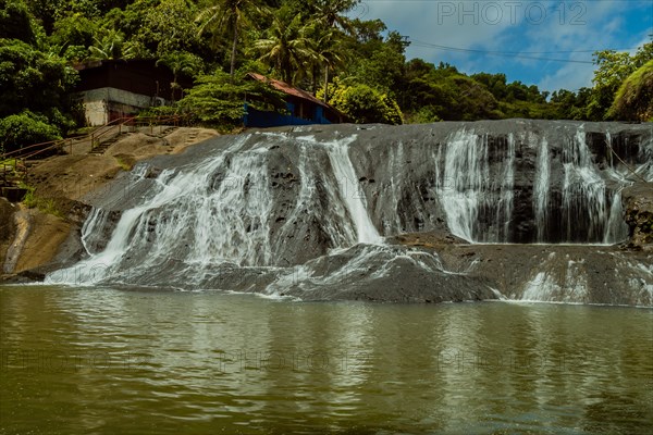Landscape of a waterfall taken with ND filter with trees and blue sky in the background and water