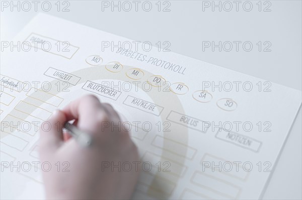 Diabetes log, daily log of food and insulin administration, food log, hand of a child holding a pen