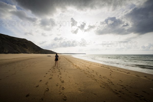 Young woman walking on the beach, emotion, rock, distance, cloudy, cloudy, mood, atmosphere, alone,