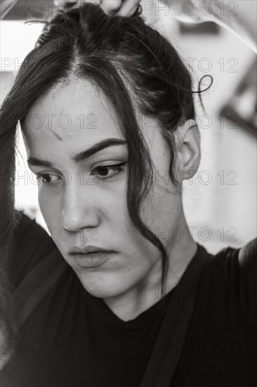 Hispanic latino long haired brunette sexy woman mechanic examining a car part in a well-equipped