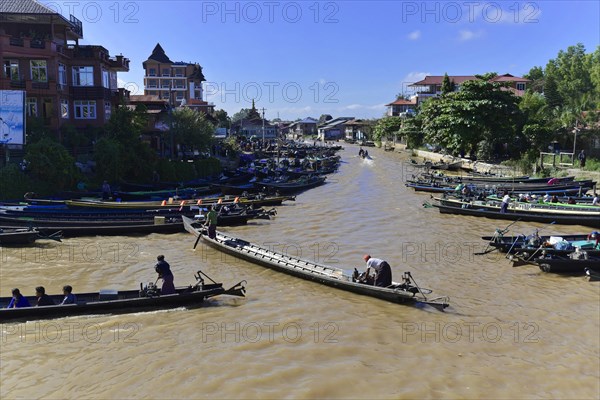 People on boats on a river with city silhouette in the background, Pindaya, Inle Lake, Myanmar,
