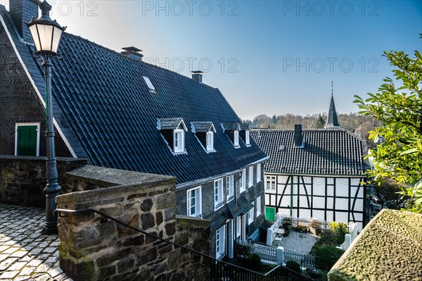 View of an alley with historic half-timbered houses and a church spire in the background,