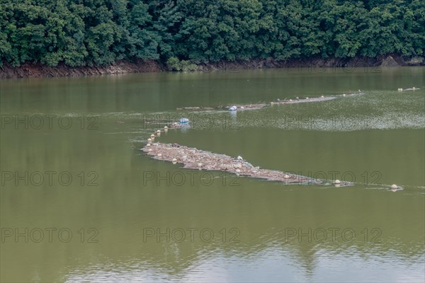 Island of trash and debris in reservoir being collected by net in Daejeon South Korea