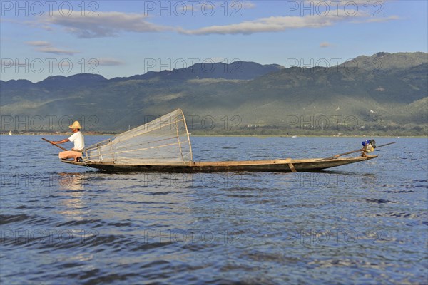 Fishermen on a boat in sunny weather, picturesque mountain scenery in the background, Inle Lake,