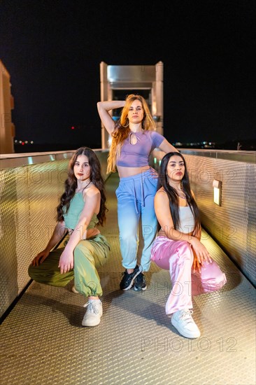 Vertical portrait of a group of three beauty young breakdancers posing together at night in a