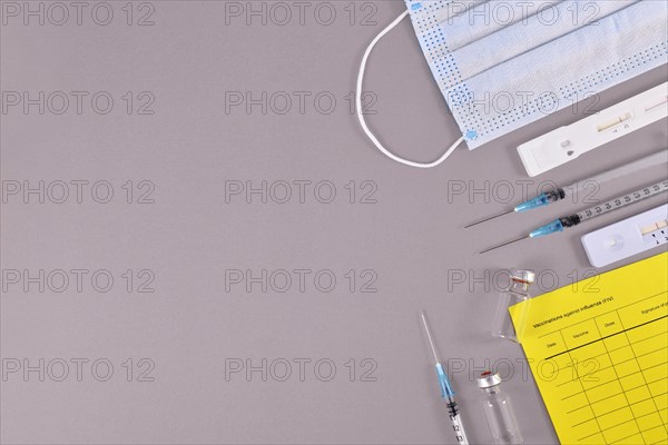 Virus antigen test, vaccine passport, medical face masks, vaccine vials with syringes on gray