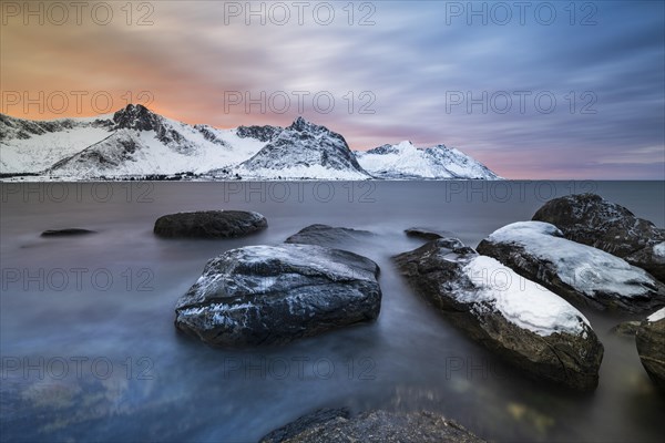 Rocky coast at the fjord with snow-covered mountains at sunset, Steinfjorden, Tungeneset,