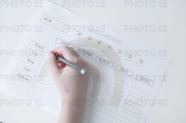 Diabetes log, daily log of food and insulin administration, food log, hand of a child holding a pen