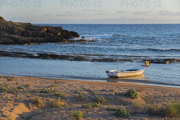 Tranquil scene of a single boat on the coastline with rocks in the soft evening light, Finikounda,