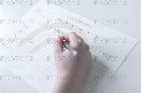 Diabetes log, daily log of food and insulin administration, food log, hand of a child holding a pen