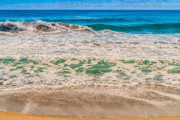 Seascape of whitecaps and waves as tide rolls in to shore on beautiful winter morning under partly