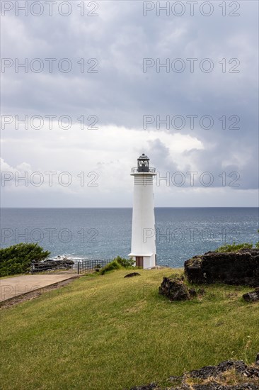 White lighthouse on a steep coast. Dramatic clouds with a view of the sea, pure Caribbean at Le