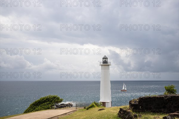 White lighthouse on a steep coast. Dramatic clouds with a view of the sea, pure Caribbean at Le