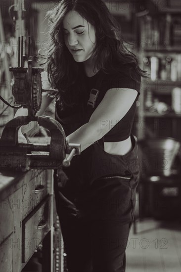 Craftswoman engaged in work using a vise on a bench in workshop, real women performing traditional