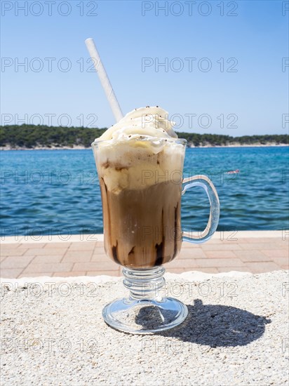 Iced coffee with whipped cream, the sea in the background, Rab Island, Kvarner Gulf Bay, Croatia,