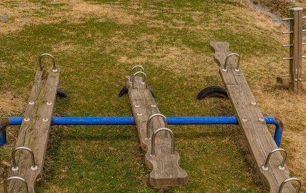 Wooden seesaw playground equipment on a well-maintained grassy field, in South Korea