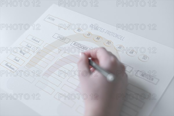 Diabetes log, daily log of food and insulin administration, food log, hand of a child holding a pen