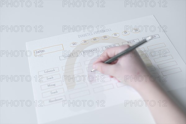 Diabetes log, daily log of food and insulin administration, food log, hand of a child holding a pen