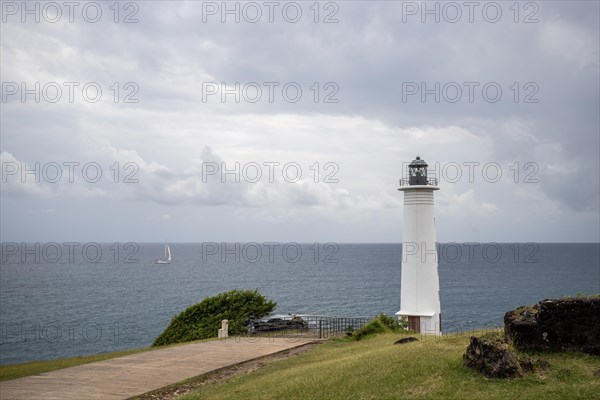 White lighthouse on a steep coast. Dramatic clouds with a view of the sea, pure Caribbean at Le