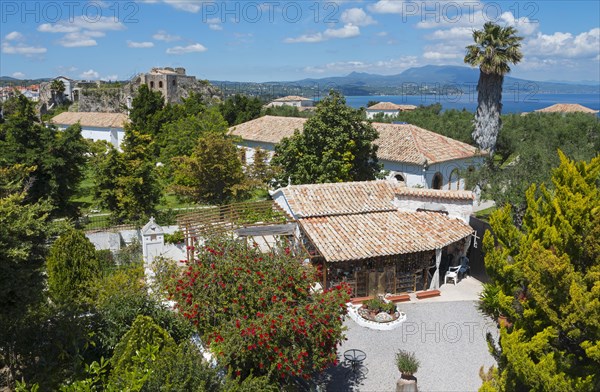 Monastery with buildings with terracotta roofs, sea view and a castle in the background, on the