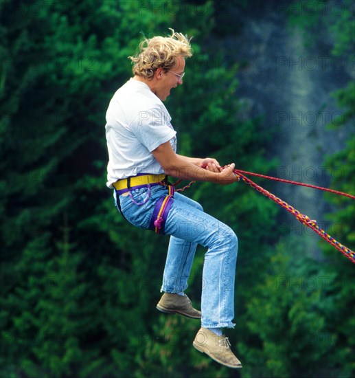 Man, about 24 years old, jumping on a climbing rope secured by the bridge, Echelsbacher Bridge,