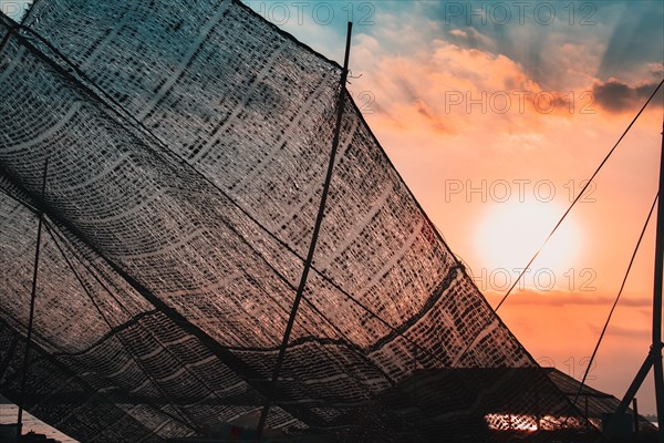 Close up of fishing nets hanged to dry and backlit by the sunset light in Mekong Delta, Vietnam,