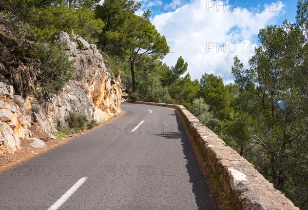 Winding, very narrow mountain road on a steep rocky slope, lined with rocks (limestone) and