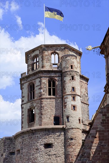 The top of a historic tower with flag and battlements (Heidelberg Castle), under a blue sky,