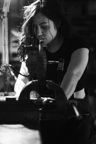 Hispanic latino long haired brunette sexy woman mechanic examining a car part in a well-equipped