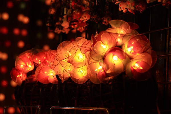 Glowing round paper lanterns on display at a market with soft, warm lighting and bokeh background.