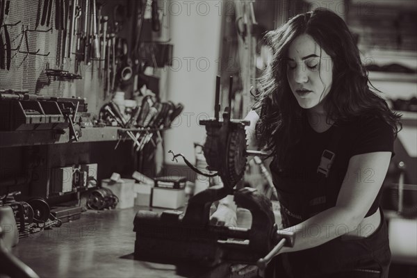 Craftswoman focused on a task at her workbench amid various tools, real women performing