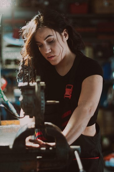 Female technician in the midst of workshop activity, skillfully fixing a component with focus, a
