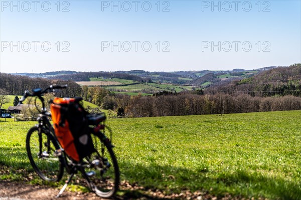 Packed bicycle in front of picturesque spring landscape with green meadows and blue sky,