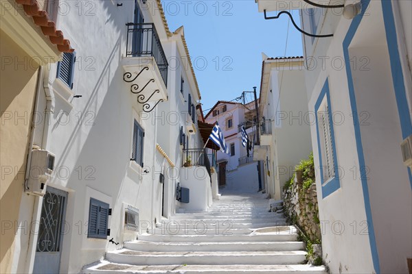 A sun-drenched alleyway with white houses and blue accents in Koroni, Pylos-Nestor, Messinia,