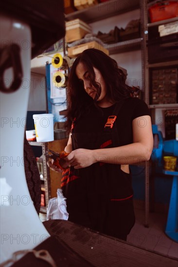 Hispanic young sensual long haired brunette Mechanic with a draper applying detail to a classic