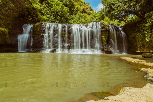 Landscape of a waterfall taken with ND filter with trees and blue sky in the background and water