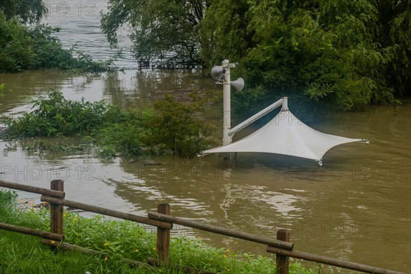 White awning over flooded river where picnic table has been submerged under water from monsoon