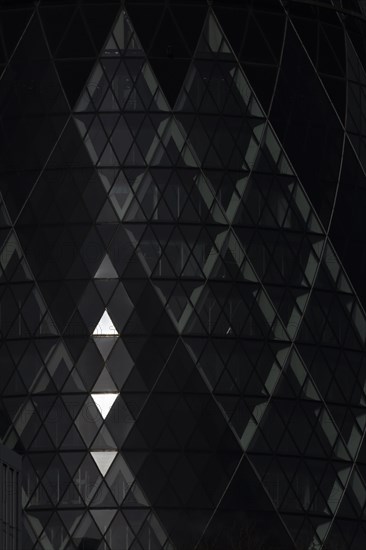 The Gherkin skyscraper building close up of window details with sunlight illuminating three