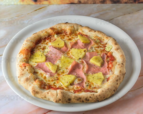 Tropical Hawaiian pizza with pineapple slices and ham on a baked dough base served whole with