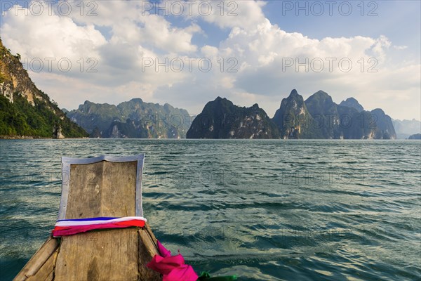 Traditional longtail boat in front of limestone rocks in Cheow Lan Lake in Khao Sok National Park,
