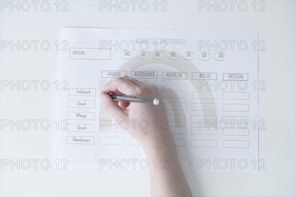 Diabetes log, daily log of food and insulin administration, food log, hand of a child holding a pen