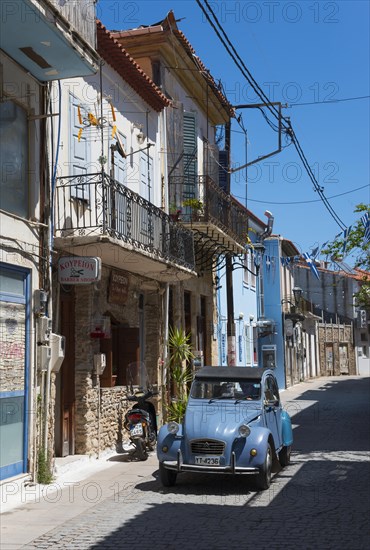 A quiet alleyway scene with old buildings, a vintage car and a motorbike, Citroen 2 CV, duck,