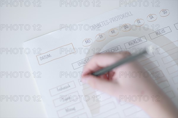 Diabetes log, daily log of food and insulin administration, food log, hand of a child holding a pen