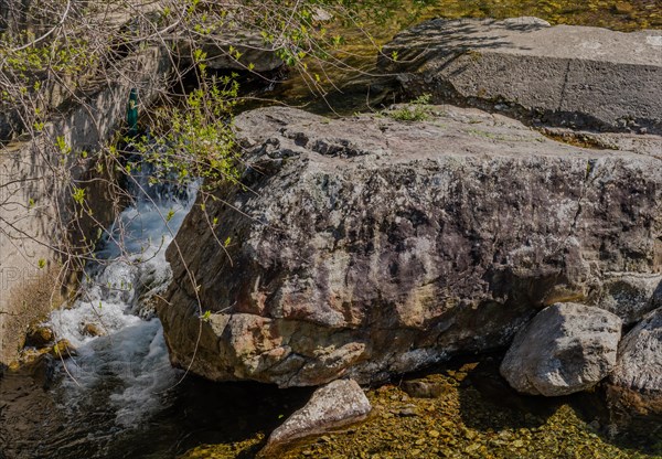 Water cascades down beside a large shaded rock, in South Korea