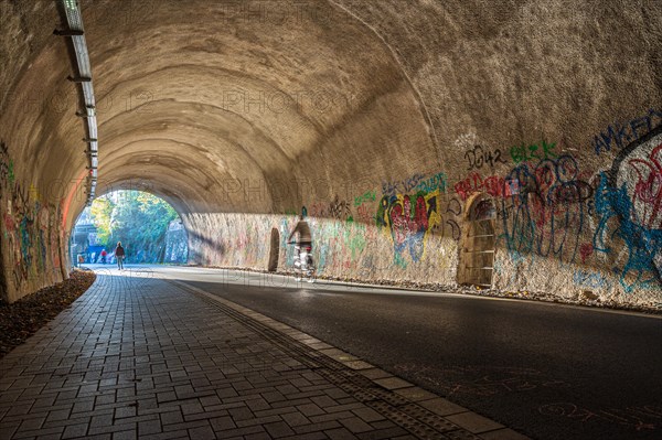 A cyclist rides through a graffiti tunnel with focussed lighting, Nordbahntrasse, Elberfeld,
