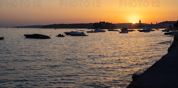 Boats anchoring in a bay, silhouette of a church tower, sunset over Rab, panoramic view, town of