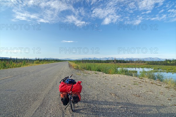 Bicycle standing on an endless straight road in the wilderness, bicycle tour, adventure trip, late