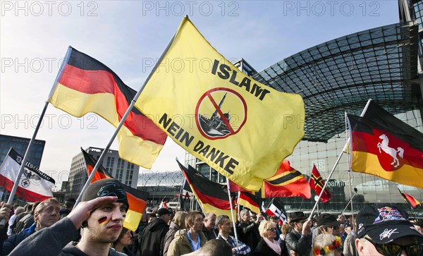 A participant in the Merkel muss weg demonstration holds a flag with the inscription Islam nein
