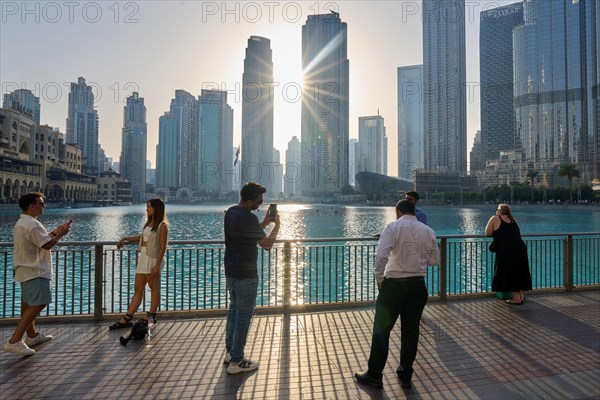 Tourists in front of the skyscraper backdrop at Lake Burj Khalifa. Dubai, United Arab Emirates,